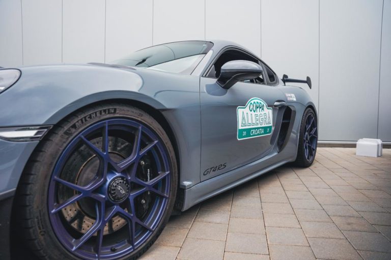 Zu sehen ist ein grauer Porsche mit Coppa Allegra Aufkleber