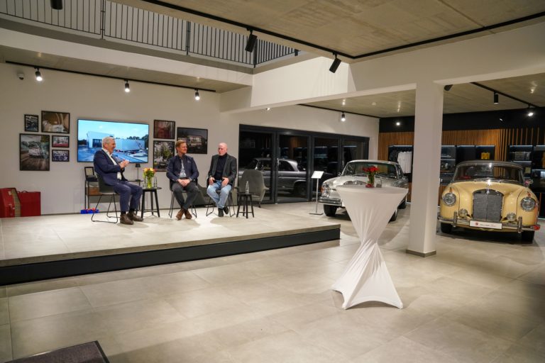 Rouven Genz auf einem Podium mit zwei weiteren Personen im Wallner Classic Verkaufsraum