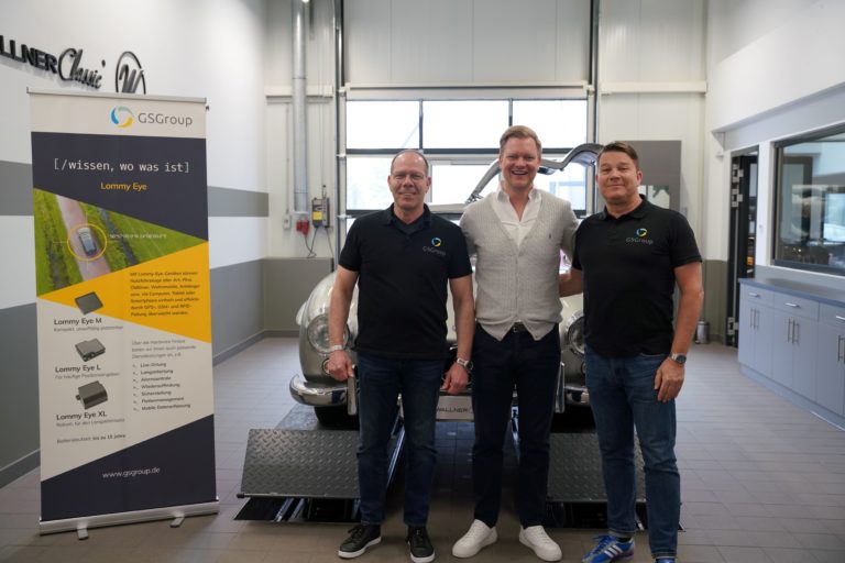 Zu sehen ist Herr Genz vor einem Mercedes 300 SL mit zwei weiteren Personen. Neben der Gruppe ist ein Banner der GSG Gruppe aufgestellt.