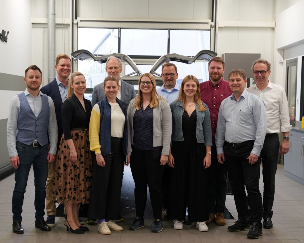 Eine Gruppe Personen vor einem 300 SL in der Werkstatt von Wallner Classic