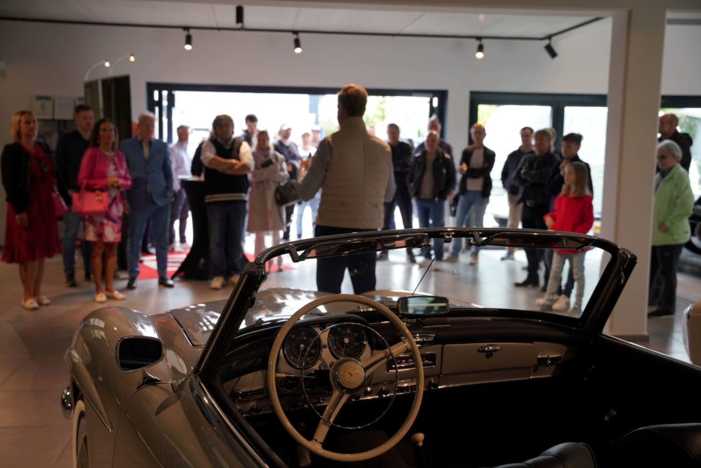 Zu sehen ist Herr Genz der einer Gruppe Personen im Ausstellungsraum einen Vortrag hält.